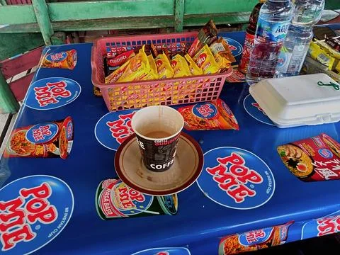 A cup of coffee is on a table with a Pop Mie tablecloth Фото