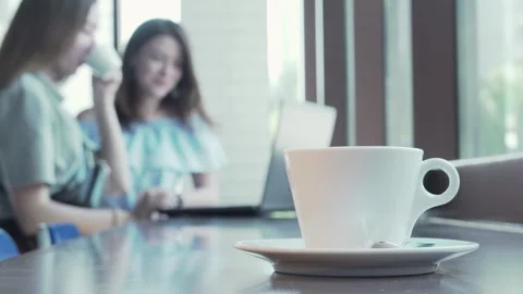 Cup of coffee on the table as two female students collaborate on a project Stock Footage 311944628