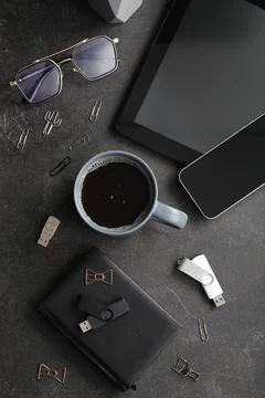 Cup of coffee with tablet computer, mobile phone and USB flash drives on blac Stock Photos