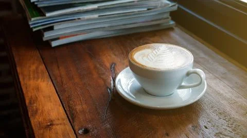 A cup of coffee was put in a stack of a book. Stock Photos
