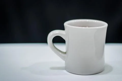 A cup of coffee on the white table and a black background Stock Photos