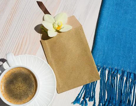 A cup of coffee on a white table. Envelope with Orchid. Romantic morning. Stock Photos