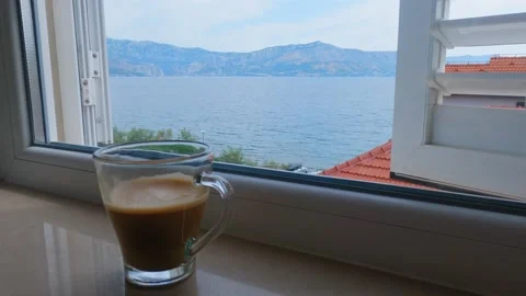 A cup of coffee on the window of the apartment overlooking the sea Stock Footage 160466674