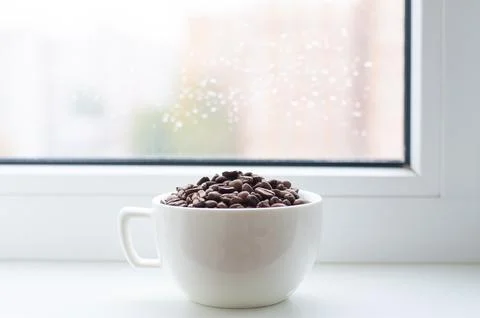 A cup of coffee is on the windowsill by the window 스톡 사진
