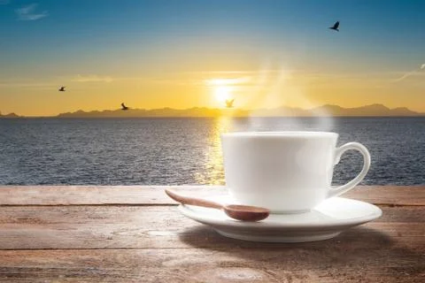 Cup of coffee on a wooden table at sea view. Stock Photos