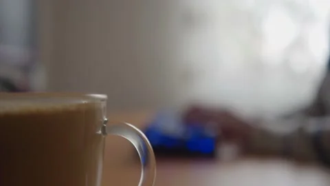 Cup of coffee on a work table and hands typing on the keyboard in the background Stock-Footage 234121638