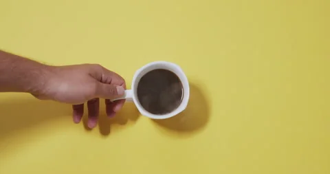 Cup of coffee on a yellow background. man's hand taking a cup of drink. Stock Footage 201170246