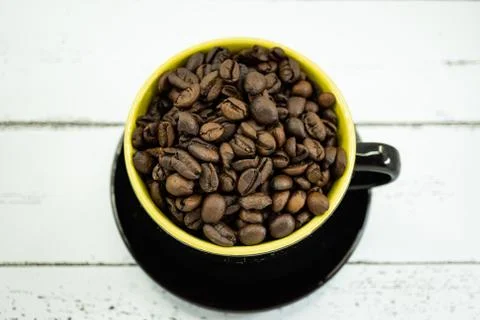 A cup of coffeeCoffee beans in a cup on white wooden background. Stock Photos