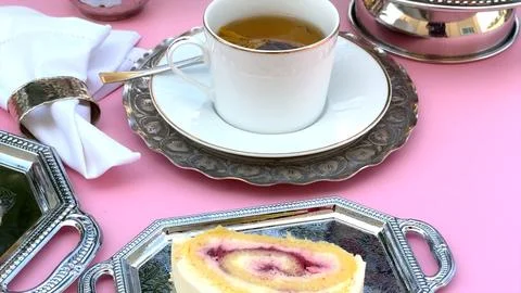 Cup displayed alongside cake roll featuring creamy cake swirls and berry Stock Photos