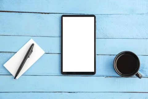 A Cup of drink ,a black tablet ,a small paper notebook and a black pen on a b Stock Photos