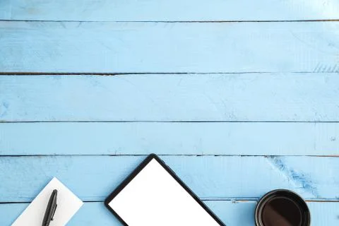 A Cup of drink ,a black tablet ,a small paper notebook and a black pen on a b Stock Photos