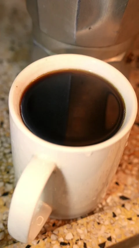 A cup of espresso next to a Moka pot. Hot steam rises from a coffee cup Stock Footage 342301458