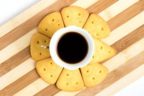 A cup of espresso stands on a round surface of cookies on a striped board. Stock Photos