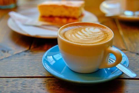 Cup of fancy coffee with a white decorated pattern next to a cookie Stock Photos
