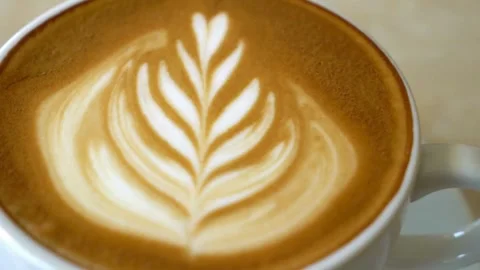 A cup is filled with coffee and steamed milk, topped with beautiful latte art. Vídeo Stock 334650526