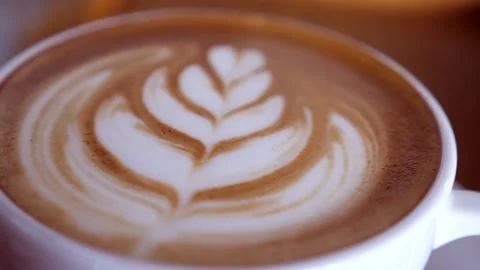 A cup is filled with coffee and steamed milk, topped with beautiful latte art. 動画素材 334650538
