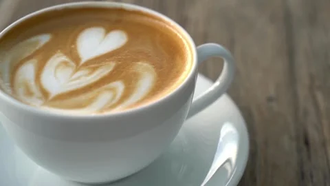 A cup is filled with coffee and steamed milk, topped with beautiful latte art. 動画素材 334650727