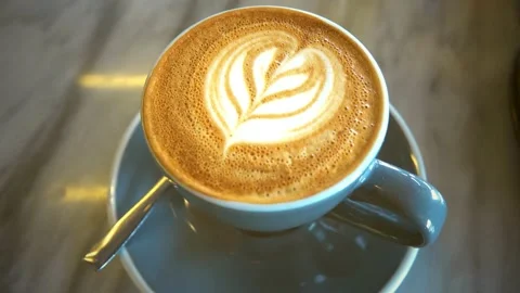 A cup is filled with coffee and steamed milk, topped with beautiful latte art. 動画素材 334650734