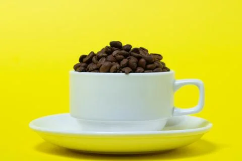 Cup filled with coffee beans on a yellow background. Freshly roasted coffee bean Stock Photos