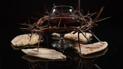 Cup filled with wine surrounded by Jesus crown of thorns and Bread. Communion Stock Footage 128608764