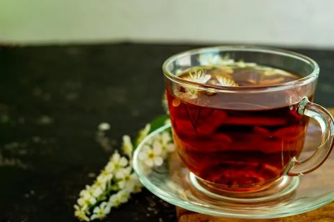 A cup of flower tea with spring cherry blossom on a black background. Copy sp Stock Photos