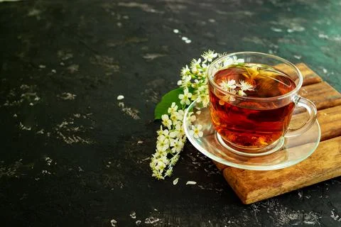 A cup of flower tea with spring cherry blossom on a black background. Copy sp Stock Photos