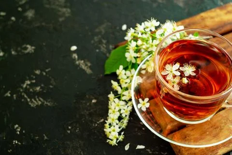 A cup of flower tea with spring cherry blossom on a black background. Copy sp Stock Photos
