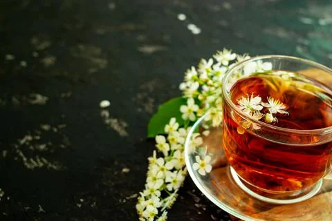 A cup of flower tea with spring cherry blossom on a black background. Copy sp Stock Photos