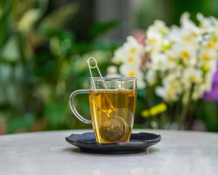 Cup of fresh aromatic tea on table with nature flowers background Stock-Fotos