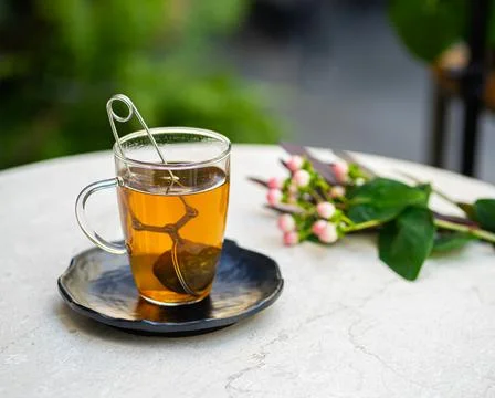 Cup of fresh aromatic tea on table with nature flowers background Stock Photos