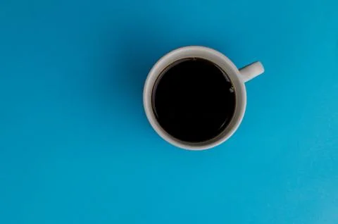 A cup of fresh coffee on blue background with text space. Flat lay. Top view. Stock Photos