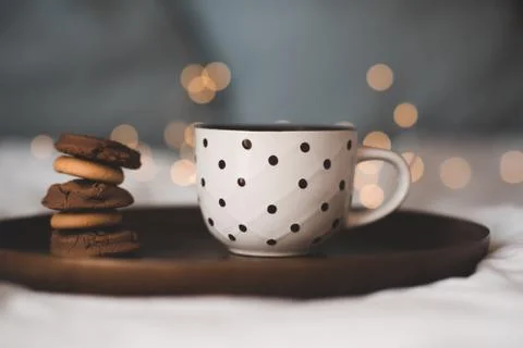 Cup of fresh hot tea with stack of chocolate cookies on wooden tray in bed cl Stock-Fotos