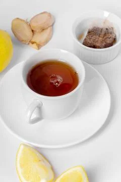 A cup of fresh tea with lemon, ginger, and tea bag. White background, isola.. Stock Photos