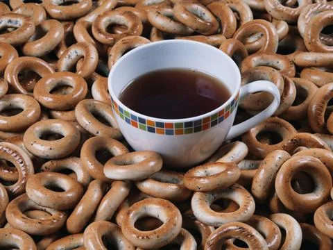 A cup of freshly brewed tea surrounded by bagels 스톡 사진