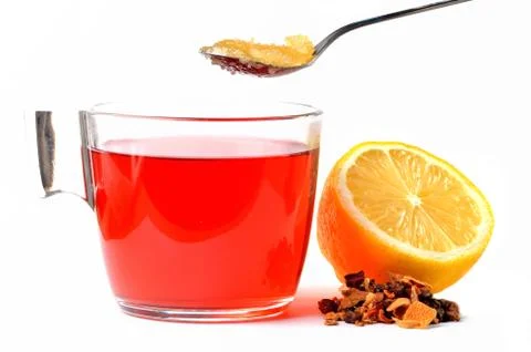 Cup of fruit tea, half pieced lemon, heap of dried tea and teaspoon of honey Stock Photos