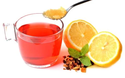 Cup of fruit tea, half pieced lemon, heap of dried tea and teaspoon of honey Stock Photos