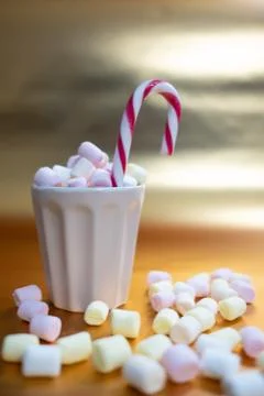 Cup full of marshmallows and a candy cane, marshmallows on the table surface Stock Photos