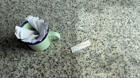 A cup full of paper packaged toothpicks and a toothpick on a marble table Stock Footage 329095745
