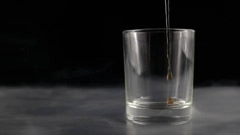 In a Cup on a gray table pouring a cola on a black smoky background Stock Footage 124276310
