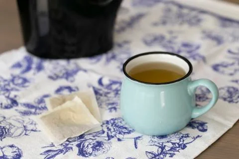 A cup of green tea on a coffee table with black kettle on the background. Stock Photos