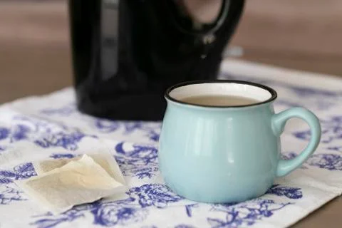 A cup of green tea on a coffee table with black kettle on the background. Stock Photos