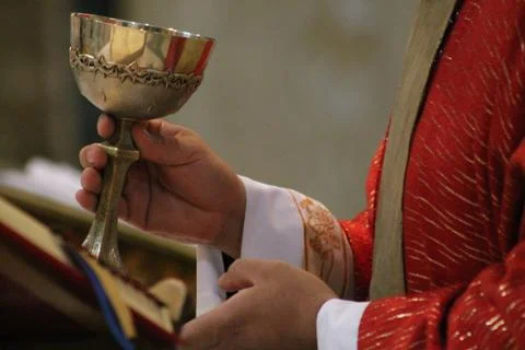 Cup in the hands of a priest 스톡 사진