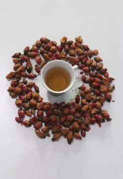 A cup of herbal tea surrounded by dried rose flower buds  Fotos Stock