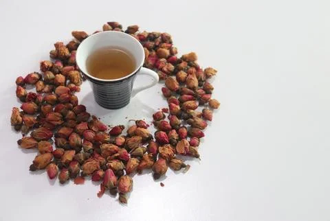 A cup of herbal tea surrounded by dried rose flower buds  Fotos Stock