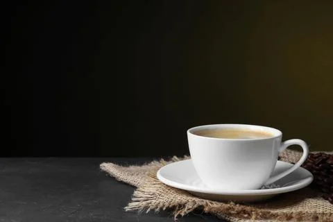 Cup of hot aromatic coffee and roasted beans on black table against dark ba.. Stock Photos
