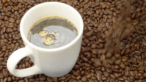 A cup of hot black coffee, with fresh beans being poured. Stock Footage 239066465