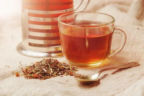 Cup of hot black tea, dried tea leaves on a light sackcloth background Stock Photos