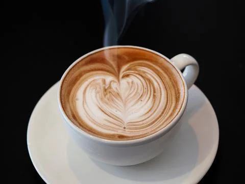 A cup of hot cafe latte (plus its latte art) served at a cafe. Stockfoto's