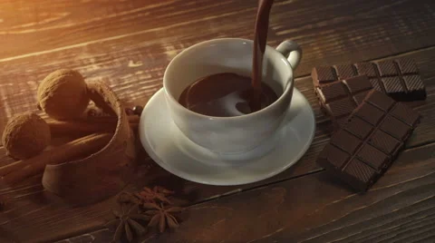 Cup of hot chocolate, cinnamon sticks, nuts and chocolate bar on wooden table Stock Footage 65791825