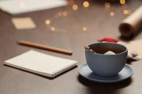 Cup of hot chocolate next to notepad and christmas decorations Stock Photos